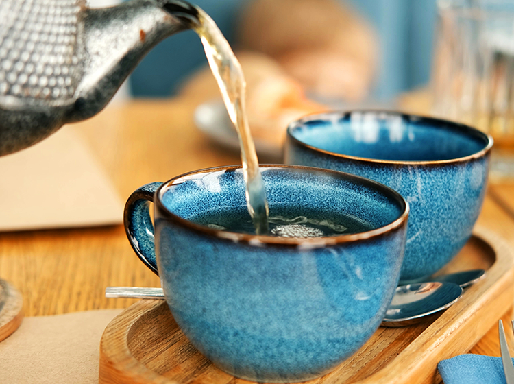 お茶をティーカップに注いでいるイメージの画像